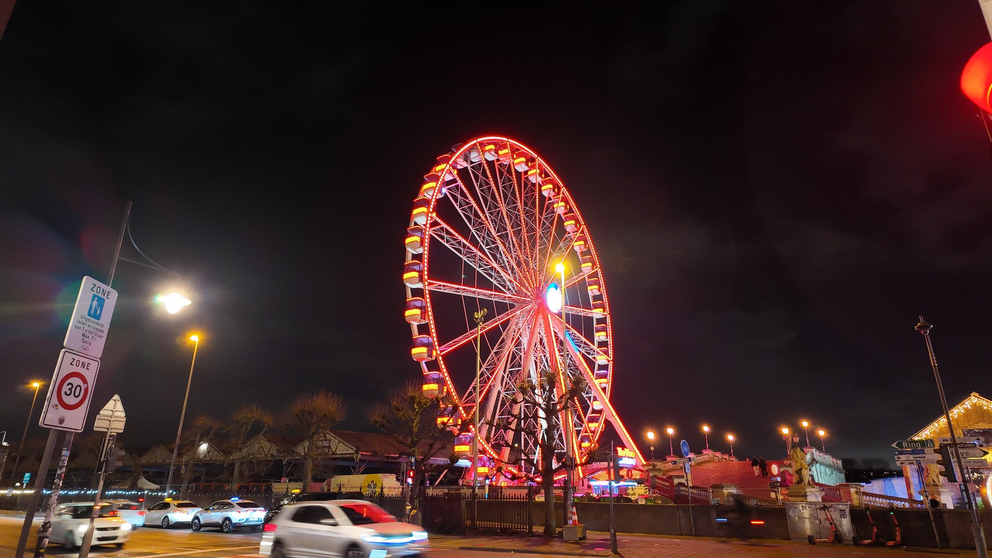 A red-lit ferris wheel called The View at Antwerp's winter market, with real Belgian street signage in the foreground